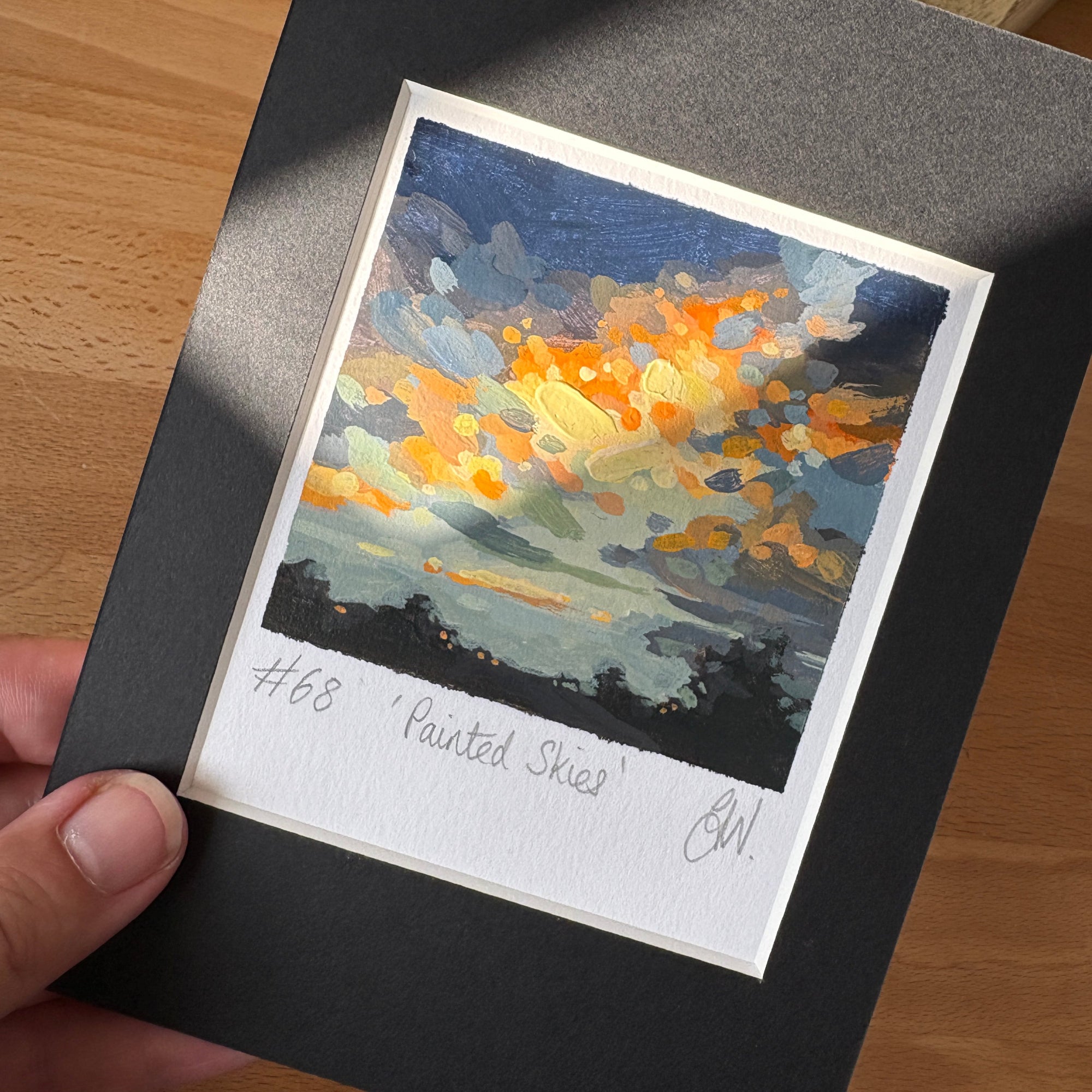 Artistic depiction of a sunset with vibrant colors held against a black background