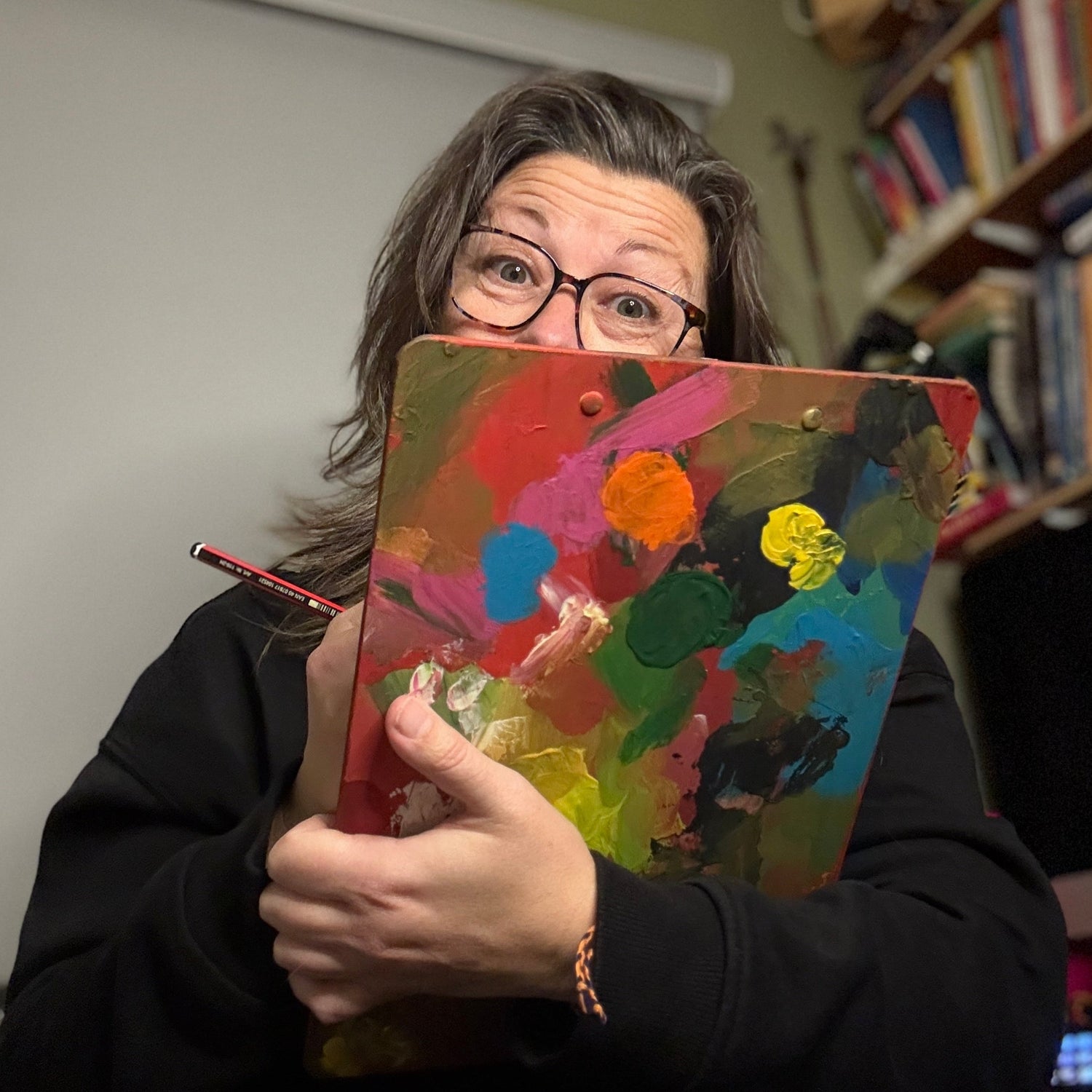 Georgina Westley holding a colourful painting in a home setting