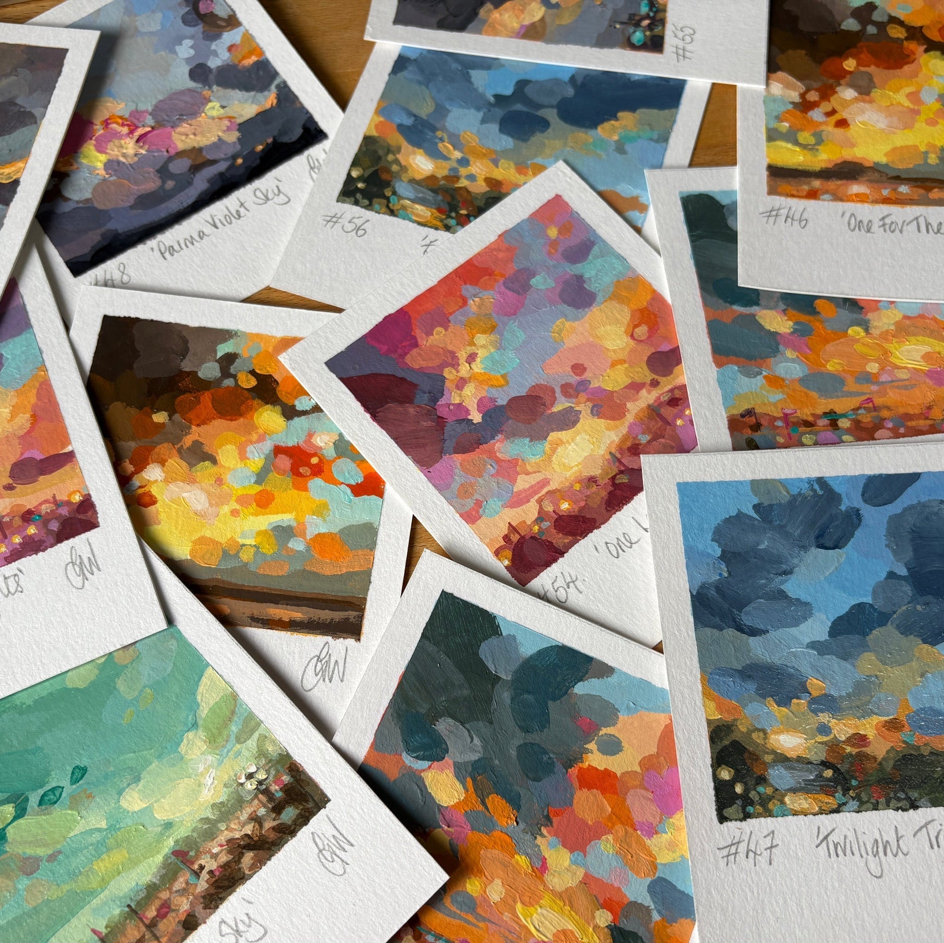 Collection of colorful abstract paintings on white cards with names underneath.