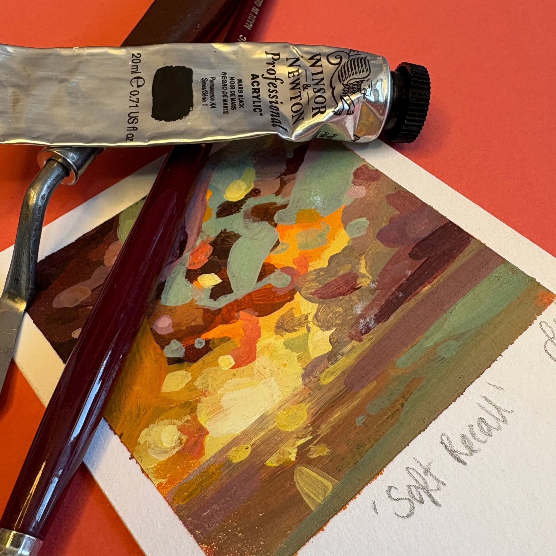 Paint tube and brush on a painting with a red background